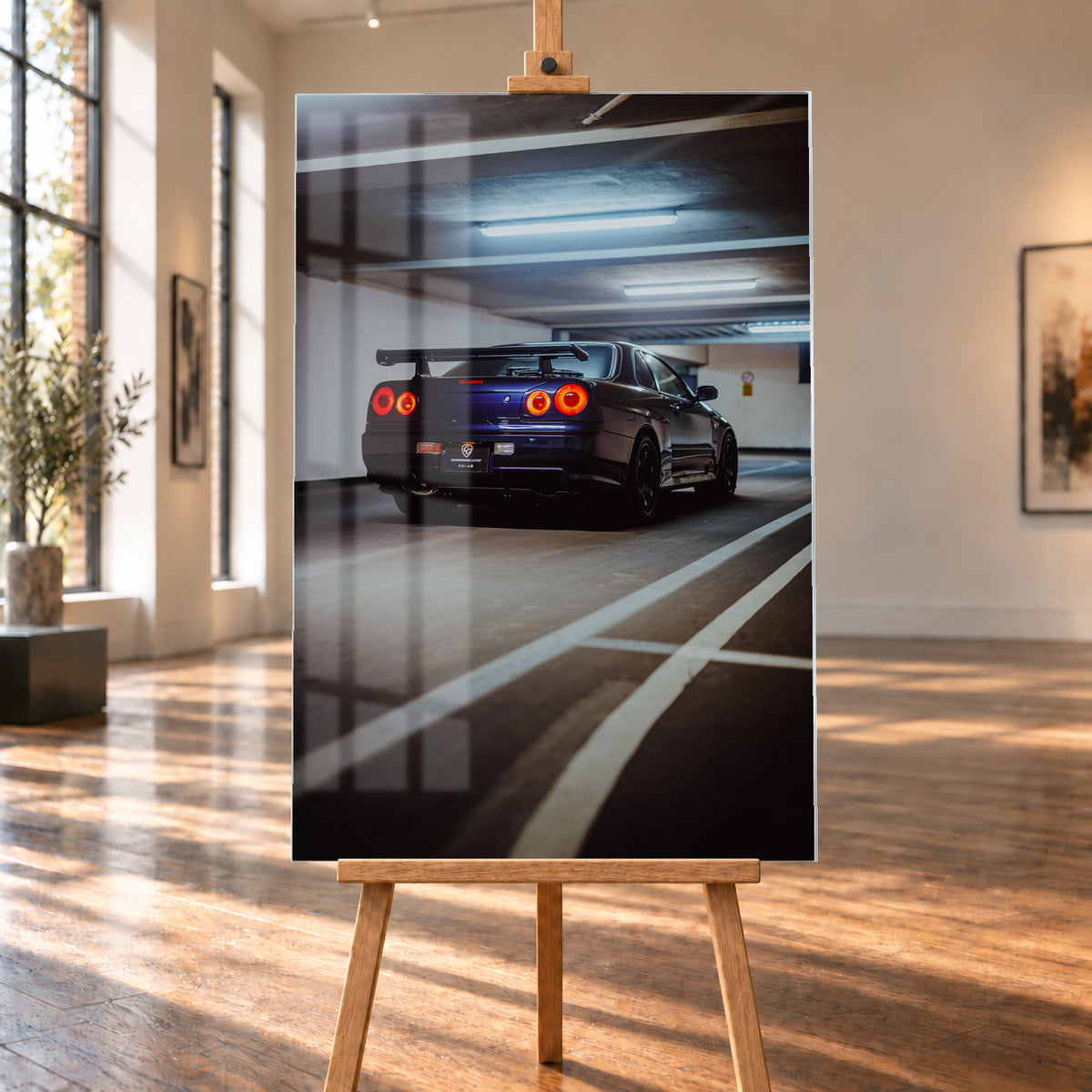 Dunkelblauer Nissan Skyline R34 in tiefer Dreiviertel-Heckansicht in einer Parkgarage; vier rote Rundrücklichter leuchten unter kühlen Deckenlampen, weiße Bodenlinien führen durch das Hochformat; Visualisierung als Acrylglas-Wandbild, auf einer Holzstaffelei in einem hellen Galerieraum.