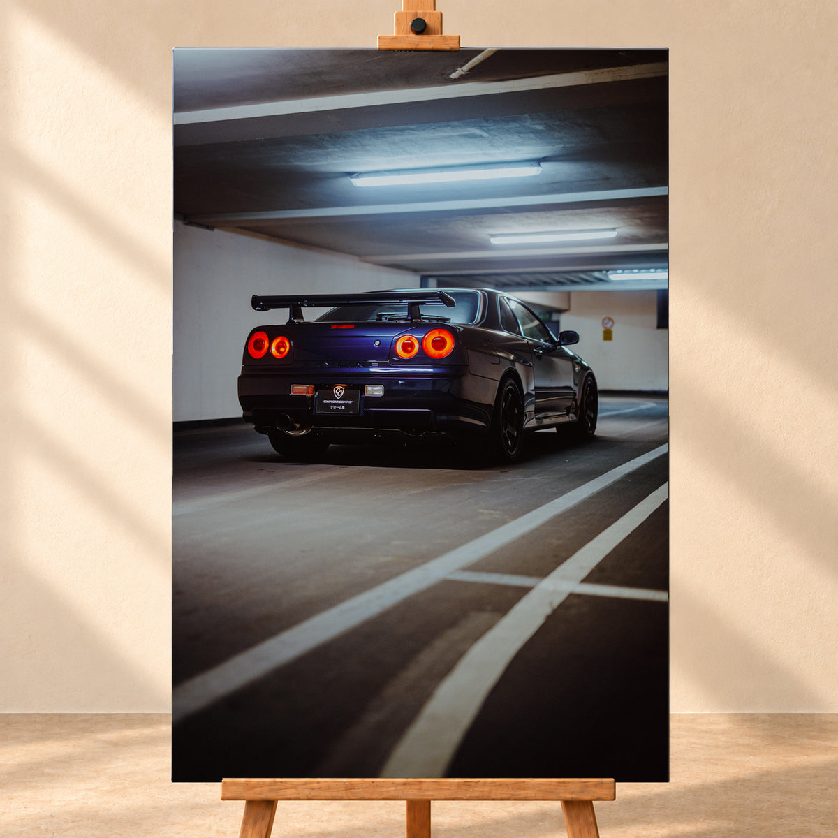 Dunkelblauer Nissan Skyline R34 in tiefer Dreiviertel-Heckansicht in einer Parkgarage; vier rote Rundrücklichter leuchten unter kühlen Deckenlampen, weiße Bodenlinien führen durch das Hochformat; Visualisierung als Leinwand-Wandbild, frontal auf einer Holzstaffelei.