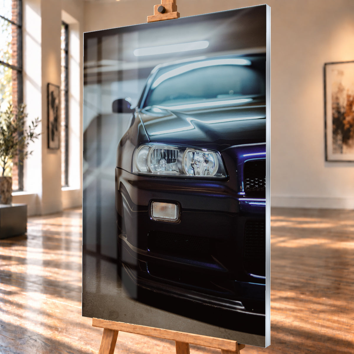Dunkler Nissan Skyline in naher, leicht versetzter Frontansicht in einem Parkhaus. Sichtbar sind Scheinwerfer, Stoßfänger, Motorhaube, Windschutzscheibe und Seitenspiegel mit kühlen blau-violetten Lichtreflexen; Visualisierung als Acrylglas-Wandbild, schräg von der Seite auf einer Holzstaffelei.