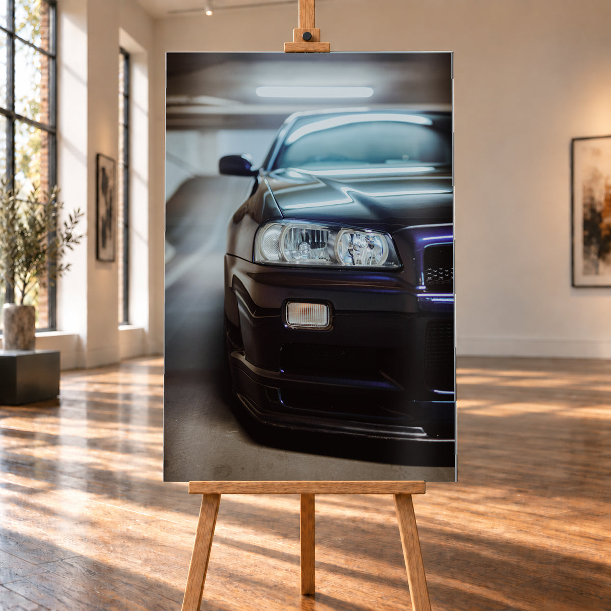 Dunkler Nissan Skyline in naher, leicht versetzter Frontansicht in einem Parkhaus. Sichtbar sind Scheinwerfer, Stoßfänger, Motorhaube, Windschutzscheibe und Seitenspiegel mit kühlen blau-violetten Lichtreflexen; Visualisierung als Alu gebürstet-Wandbild, auf einer Holzstaffelei in einem hellen Galerieraum.