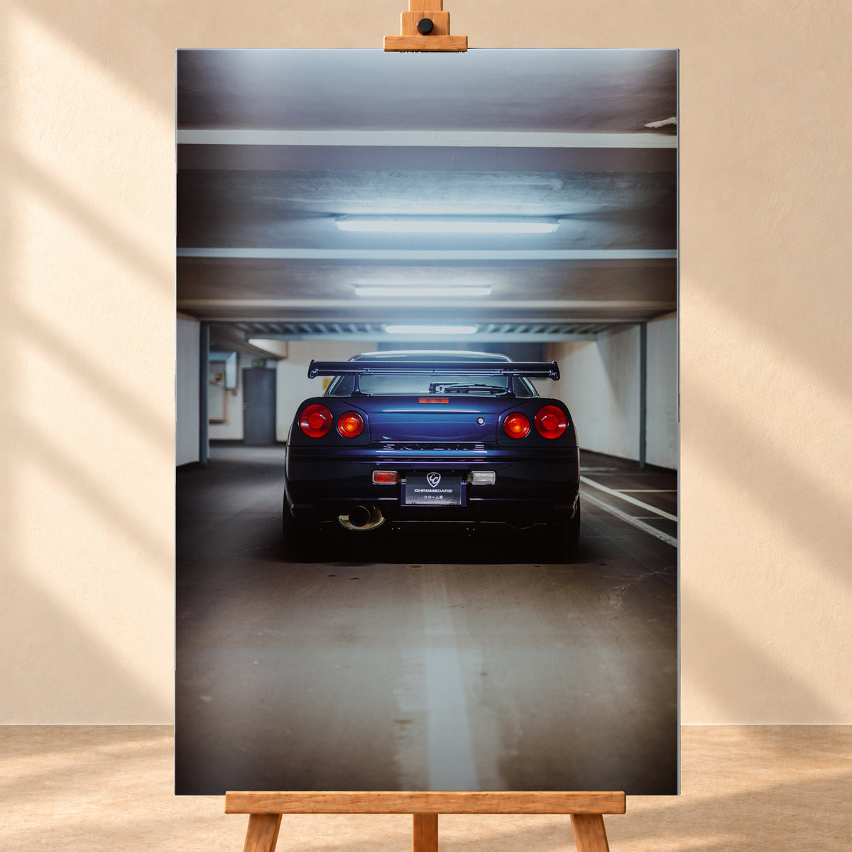 Dunkelblau bis violett wirkender Nissan Skyline R34 von hinten, mittig in einem Betonparkdeck unter kühlen Deckenleuchten; vier rote Rundlichter und ein großer Heckflügel sind sichtbar; Visualisierung als Alu gebürstet-Wandbild, frontal auf einer Holzstaffelei.