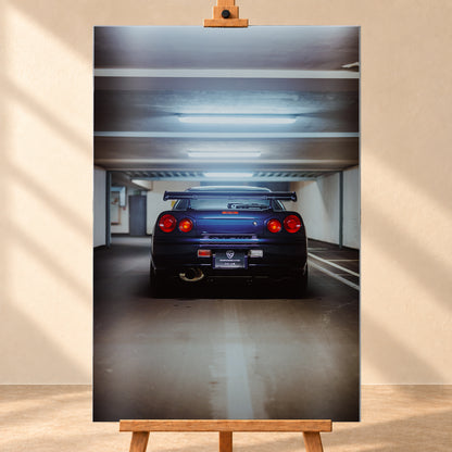 Dunkelblau bis violett wirkender Nissan Skyline R34 von hinten, mittig in einem Betonparkdeck unter kühlen Deckenleuchten; vier rote Rundlichter und ein großer Heckflügel sind sichtbar; Visualisierung als Alu gebürstet-Wandbild, frontal auf einer Holzstaffelei.
