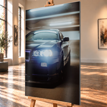Hochformatige Nahaufnahme eines dunkelblau bis schwarz wirkenden Nissan Skyline R34 in schräger Frontansicht. Ein heller Frontscheinwerfer leuchtet in die Kamera, während sich kühle rechteckige Deckenlichter auf Motorhaube und Windschutzscheibe spiegeln. Das Fahrzeug steht in einem warm beleuchteten, unscharfen Innenraum; Visualisierung als Alu gebürstet-Wandbild, schräg von der Seite auf einer Holzstaffelei.