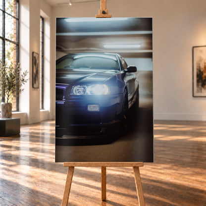 Hochformatige Nahaufnahme eines dunkelblau bis schwarz wirkenden Nissan Skyline R34 in schräger Frontansicht. Ein heller Frontscheinwerfer leuchtet in die Kamera, während sich kühle rechteckige Deckenlichter auf Motorhaube und Windschutzscheibe spiegeln. Das Fahrzeug steht in einem warm beleuchteten, unscharfen Innenraum; Visualisierung als Alu gebürstet-Wandbild, auf einer Holzstaffelei in einem hellen Galerieraum.