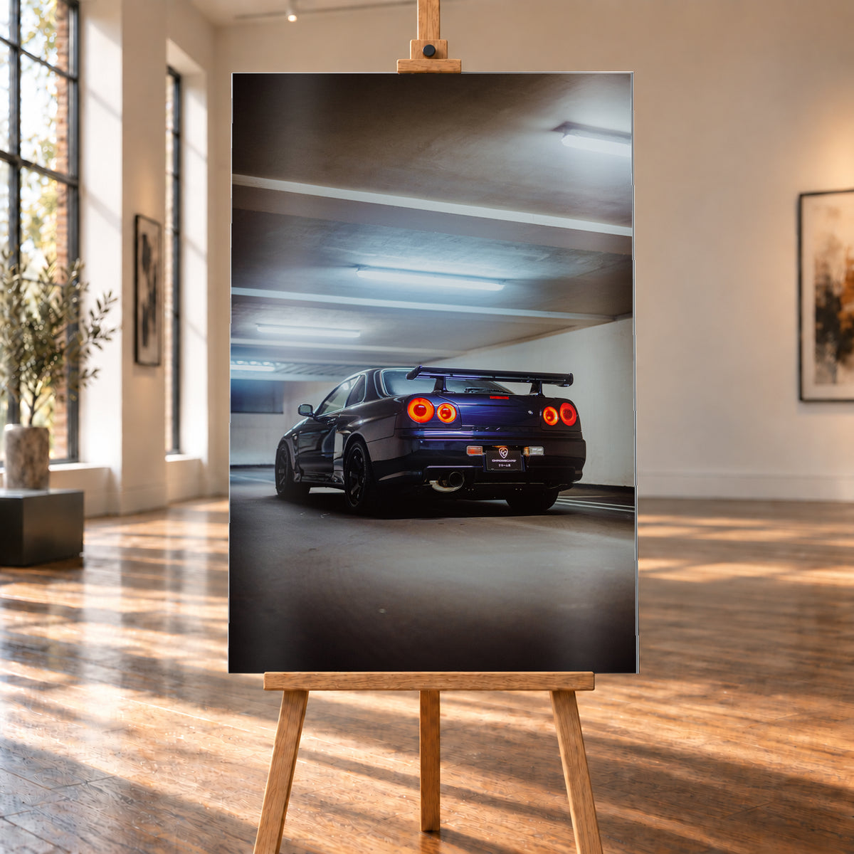 Dunkler Nissan Skyline R34 in niedriger Heck-Dreiviertelansicht mit vier rot leuchtenden Rundrückleuchten, großem Heckflügel und sichtbarem Auspuff in einer Beton-Parkgarage unter kühlen Deckenleuchten; Visualisierung als Alu gebürstet-Wandbild, auf einer Holzstaffelei in einem hellen Galerieraum.