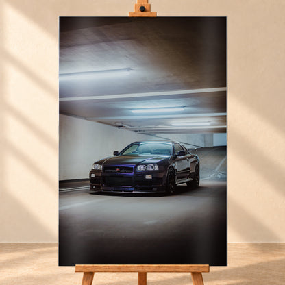 Dunkel lackierter Nissan Skyline R34 in frontaler Dreiviertelansicht in einer Betongarage mit weißen Deckenleuchten, Fahrbahnmarkierungen und ansteigender Rampe im Hintergrund; Visualisierung als Alu gebürstet-Wandbild, frontal auf einer Holzstaffelei.