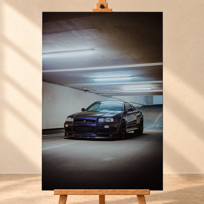 Dunkel lackierter Nissan Skyline R34 in frontaler Dreiviertelansicht in einer Betongarage mit weißen Deckenleuchten, Fahrbahnmarkierungen und ansteigender Rampe im Hintergrund; Visualisierung als Leinwand-Wandbild, frontal auf einer Holzstaffelei.