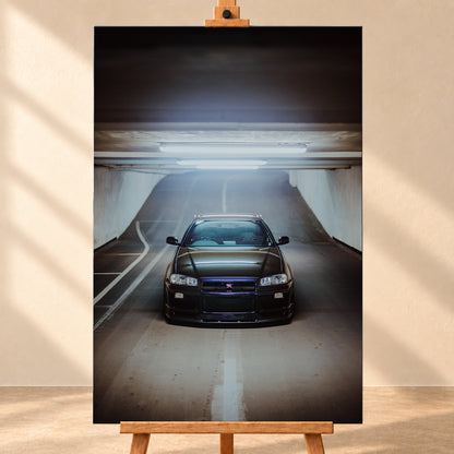 Dunkler Nissan Skyline R34 GT-R in frontaler, mittiger Ansicht auf einer ansteigenden Parkhausrampe unter hellen Deckenleuchten; weiße Fahrbahnmarkierungen, Betonwände und kühl blau-violette Reflexe prägen die Szene; Visualisierung als Leinwand-Wandbild, frontal auf einer Holzstaffelei.