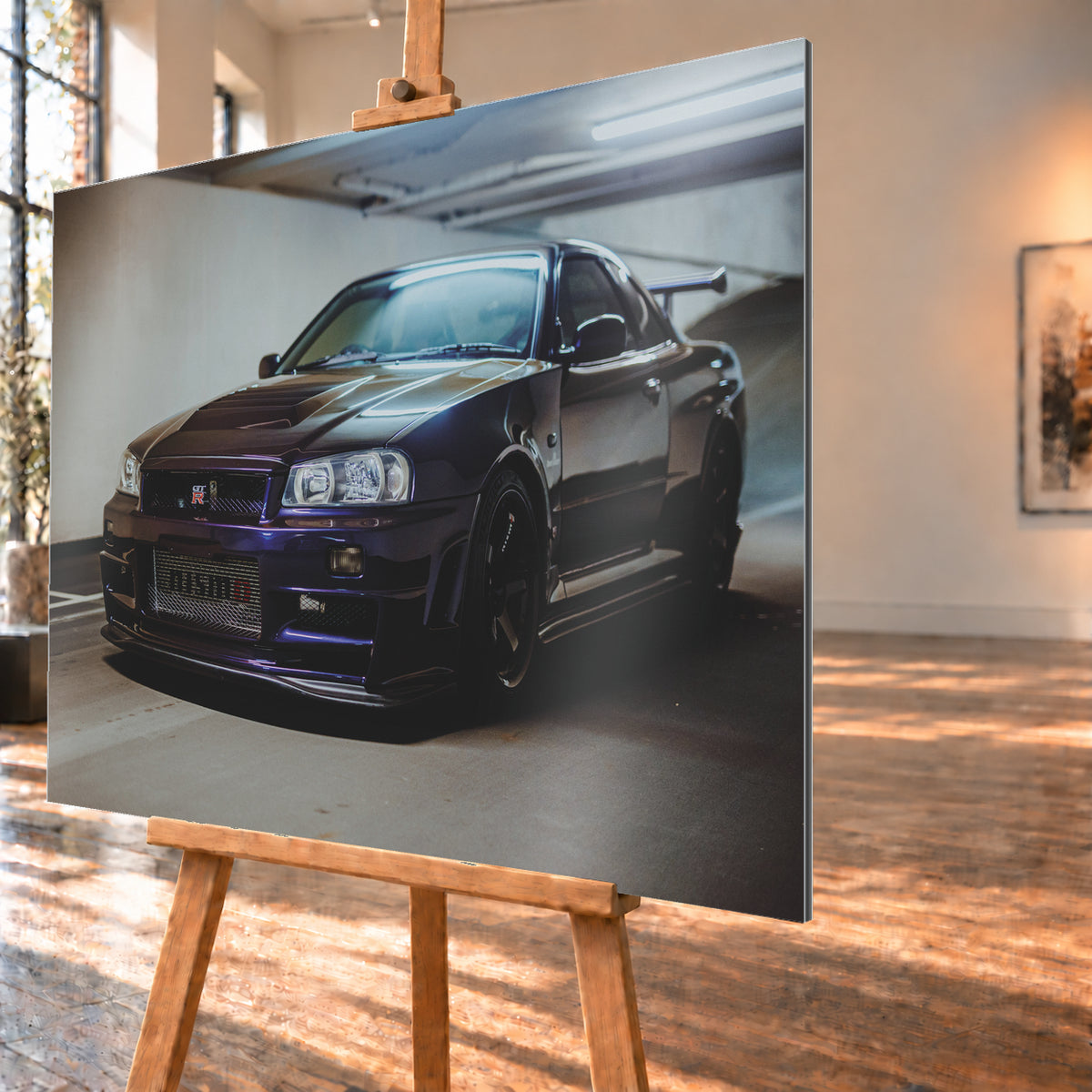 Dunkelvioletter Nissan Skyline R34 in Front-Dreiviertelansicht auf einem Parkdeck, mit schwarzem Kühlergrill, dunklen Rädern und großem Heckflügel. Helle Deckenleuchten spiegeln sich auf Motorhaube, Windschutzscheibe und Dach; Betonwand und Bodenmarkierungen rahmen das Fahrzeug; Visualisierung als Alu gebürstet-Wandbild, schräg von der Seite auf einer Holzstaffelei.