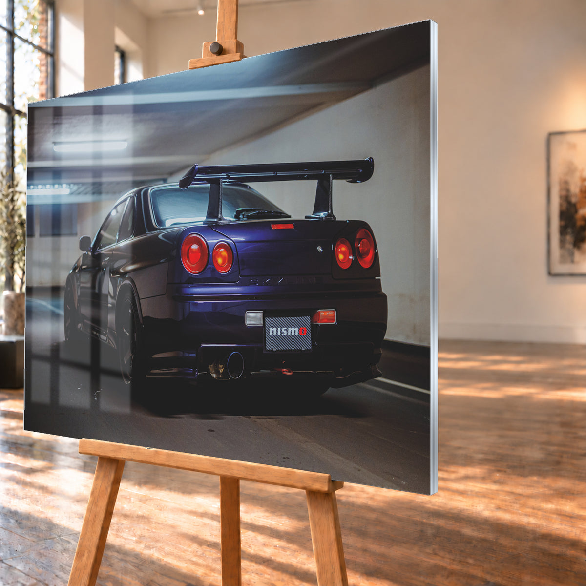 Dunkelvioletter Nissan Skyline R34 in tiefer Dreiviertel-Heckansicht in einer Beton-Tiefgarage. Zu sehen sind vier runde Rückleuchten in Rot- und Orangetönen, ein großer Heckflügel, schwarze Räder, ein großes Endrohr und ein Nismo-Schriftzug am Heck; kühles Deckenlicht spiegelt sich auf der Karosserie; Visualisierung als Acrylglas-Wandbild, schräg von der Seite auf einer Holzstaffelei.