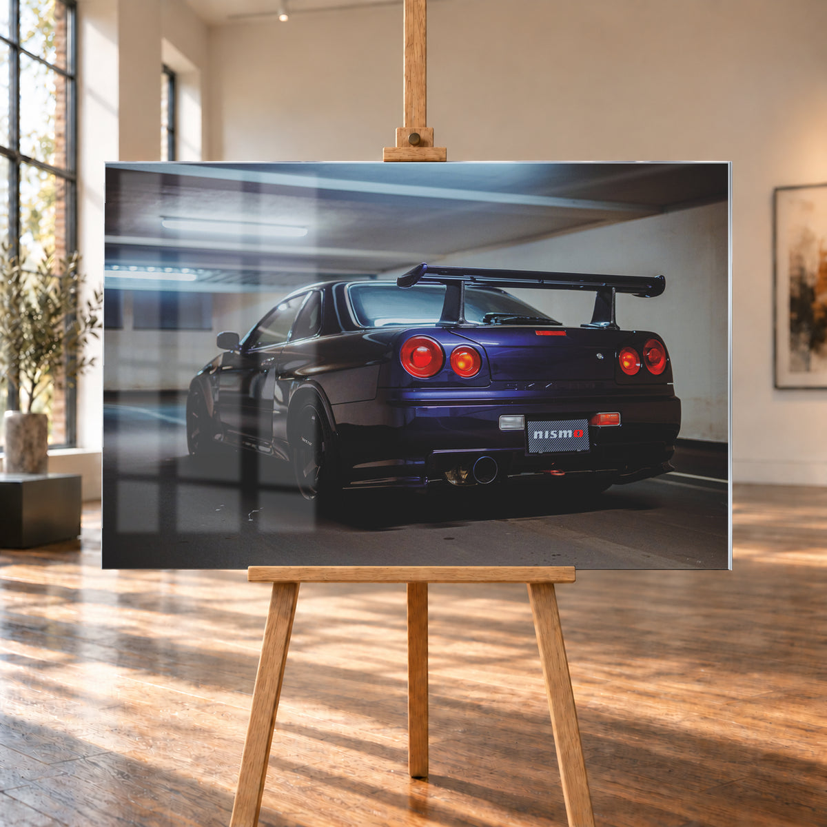 Dunkelvioletter Nissan Skyline R34 in tiefer Dreiviertel-Heckansicht in einer Beton-Tiefgarage. Zu sehen sind vier runde Rückleuchten in Rot- und Orangetönen, ein großer Heckflügel, schwarze Räder, ein großes Endrohr und ein Nismo-Schriftzug am Heck; kühles Deckenlicht spiegelt sich auf der Karosserie; Visualisierung als Acrylglas-Wandbild, auf einer Holzstaffelei in einem hellen Galerieraum.