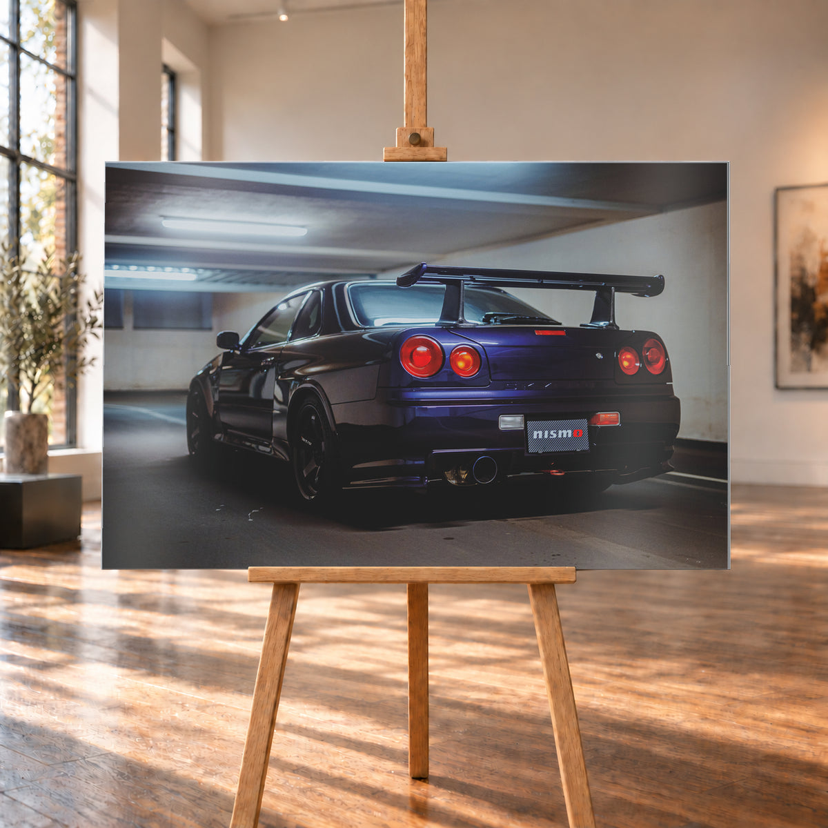 Dunkelvioletter Nissan Skyline R34 in tiefer Dreiviertel-Heckansicht in einer Beton-Tiefgarage. Zu sehen sind vier runde Rückleuchten in Rot- und Orangetönen, ein großer Heckflügel, schwarze Räder, ein großes Endrohr und ein Nismo-Schriftzug am Heck; kühles Deckenlicht spiegelt sich auf der Karosserie; Visualisierung als Alu gebürstet-Wandbild, auf einer Holzstaffelei in einem hellen Galerieraum.