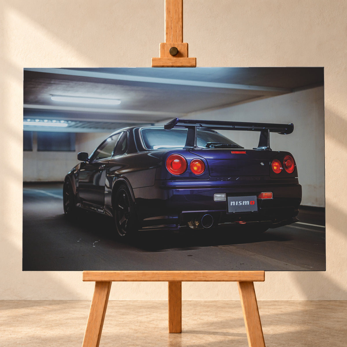 Dunkelvioletter Nissan Skyline R34 in tiefer Dreiviertel-Heckansicht in einer Beton-Tiefgarage. Zu sehen sind vier runde Rückleuchten in Rot- und Orangetönen, ein großer Heckflügel, schwarze Räder, ein großes Endrohr und ein Nismo-Schriftzug am Heck; kühles Deckenlicht spiegelt sich auf der Karosserie; Visualisierung als Leinwand-Wandbild, frontal auf einer Holzstaffelei.
