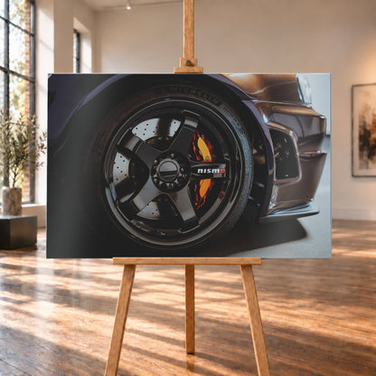 Nahaufnahme der Frontpartie eines dunkelviolett-bronze schimmernden Nissan Skyline R34 mit schwarzem Rad, sichtbarem NISMO-Schriftzug, gelochter Bremsscheibe und orange-rotem Bremssattel bei kontrastreichem Licht; Visualisierung als Alu gebürstet-Wandbild, auf einer Holzstaffelei in einem hellen Galerieraum.