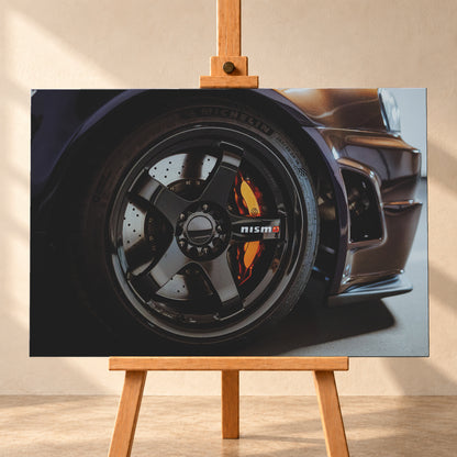 Nahaufnahme der Frontpartie eines dunkelviolett-bronze schimmernden Nissan Skyline R34 mit schwarzem Rad, sichtbarem NISMO-Schriftzug, gelochter Bremsscheibe und orange-rotem Bremssattel bei kontrastreichem Licht; Visualisierung als Leinwand-Wandbild, frontal auf einer Holzstaffelei.