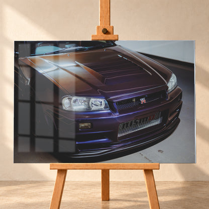 Nahes Frontporträt eines Nissan Skyline R34 in violett schimmerndem Lack, leicht von oben fotografiert, mit konturierter Motorhaube, Scheinwerfern, Kühlergrill und breiten Lufteinlässen in einem hellen Innenraum; Visualisierung als Acrylglas-Wandbild, frontal auf einer Holzstaffelei.