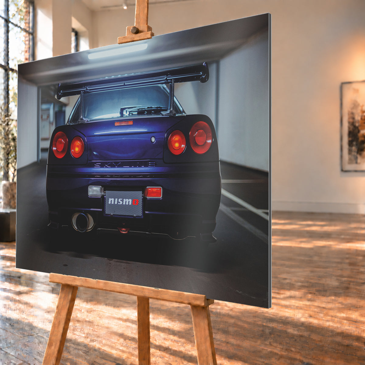 Zentrierte Heckansicht eines dunkelvioletten Nissan Skyline R34 in einer Parkgarage. Sichtbar sind vier runde rote Rückleuchten mit orangefarbenen inneren Leuchtelementen, ein großer Heckflügel, ein breites Auspuffendrohr links, ein Nismo-Schriftzug und kühles Deckenlicht über dem Fahrzeug; Visualisierung als Alu gebürstet-Wandbild, schräg von der Seite auf einer Holzstaffelei.