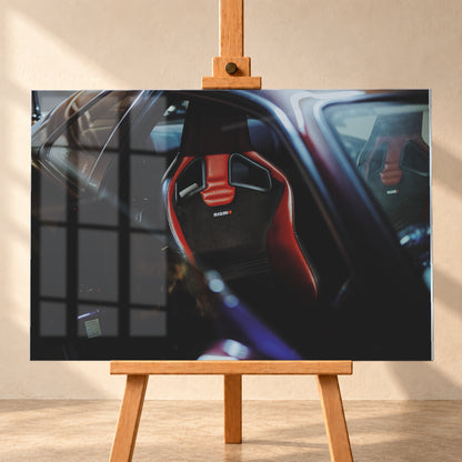 Seitlicher Nahblick in den dunklen Innenraum eines Nissan Skyline R34. Ein rot-schwarzer Sportsitz mit Öffnungen in der Rückenlehne und Nismo-Schriftzug steht im Zentrum; ein zweiter Sitz ist gegenüber sichtbar. Blau-violette Reflexe, Glasflächen und tiefe Schatten rahmen die Szene; Visualisierung als Acrylglas-Wandbild, frontal auf einer Holzstaffelei.