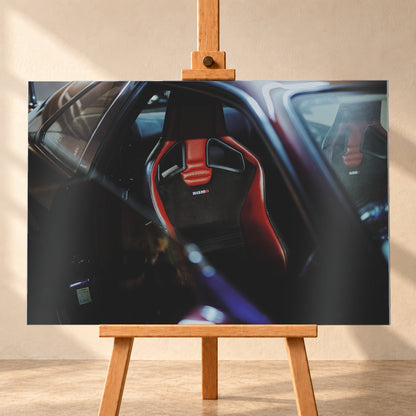 Seitlicher Nahblick in den dunklen Innenraum eines Nissan Skyline R34. Ein rot-schwarzer Sportsitz mit Öffnungen in der Rückenlehne und Nismo-Schriftzug steht im Zentrum; ein zweiter Sitz ist gegenüber sichtbar. Blau-violette Reflexe, Glasflächen und tiefe Schatten rahmen die Szene; Visualisierung als Alu gebürstet-Wandbild, frontal auf einer Holzstaffelei.