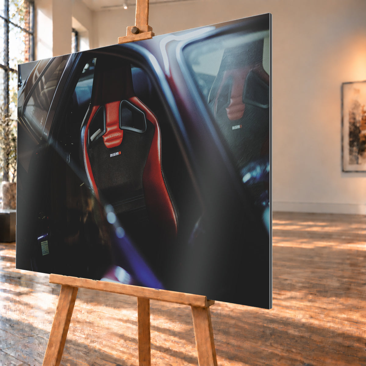 Seitlicher Nahblick in den dunklen Innenraum eines Nissan Skyline R34. Ein rot-schwarzer Sportsitz mit Öffnungen in der Rückenlehne und Nismo-Schriftzug steht im Zentrum; ein zweiter Sitz ist gegenüber sichtbar. Blau-violette Reflexe, Glasflächen und tiefe Schatten rahmen die Szene; Visualisierung als Alu gebürstet-Wandbild, schräg von der Seite auf einer Holzstaffelei.