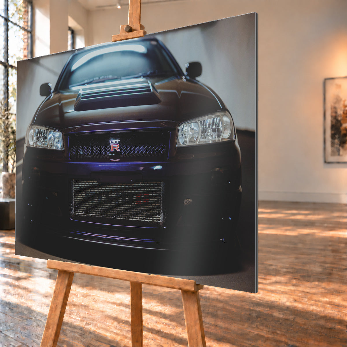 Symmetrische frontale Nahaufnahme eines dunkelvioletten Nissan Skyline R34 vor hellen Wänden. Sichtbar sind rechteckige Scheinwerfer, GT-R-Emblem, Hauben-Lufteinlass, Kühlergitter und die große untere Gitteröffnung; kühles Licht spiegelt sich auf Haube und Windschutzscheibe; Visualisierung als Alu gebürstet-Wandbild, schräg von der Seite auf einer Holzstaffelei.