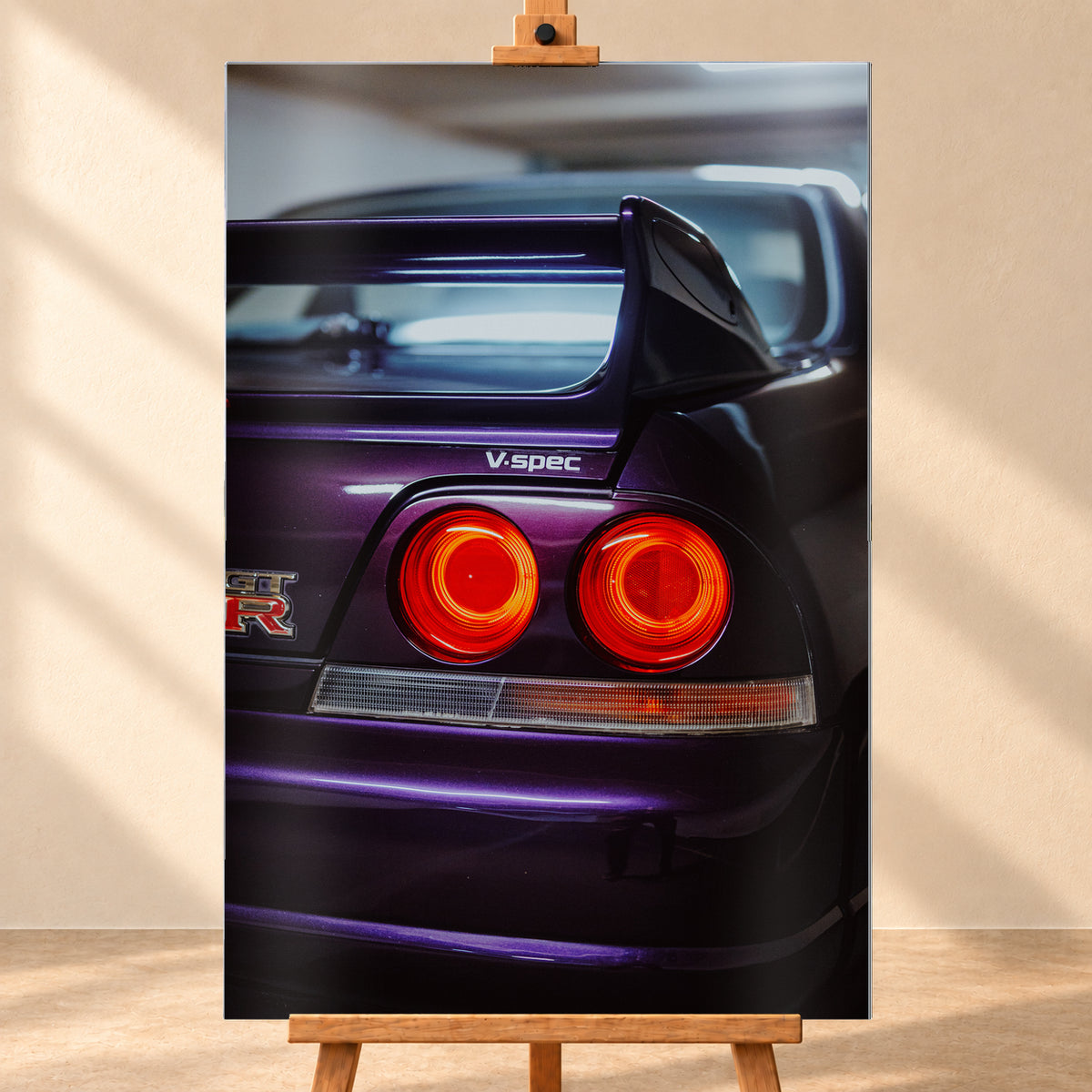Vertikale Nahaufnahme des dunkelvioletten Hecks eines Nissan Skyline V-Spec mit zwei rot leuchtenden Rundrückleuchten, GT-R-Emblem, großem Heckflügel und blau-violetten Lichtreflexen vor unscharfem dunklem Hintergrund; Visualisierung als Alu gebürstet-Wandbild, frontal auf einer Holzstaffelei.