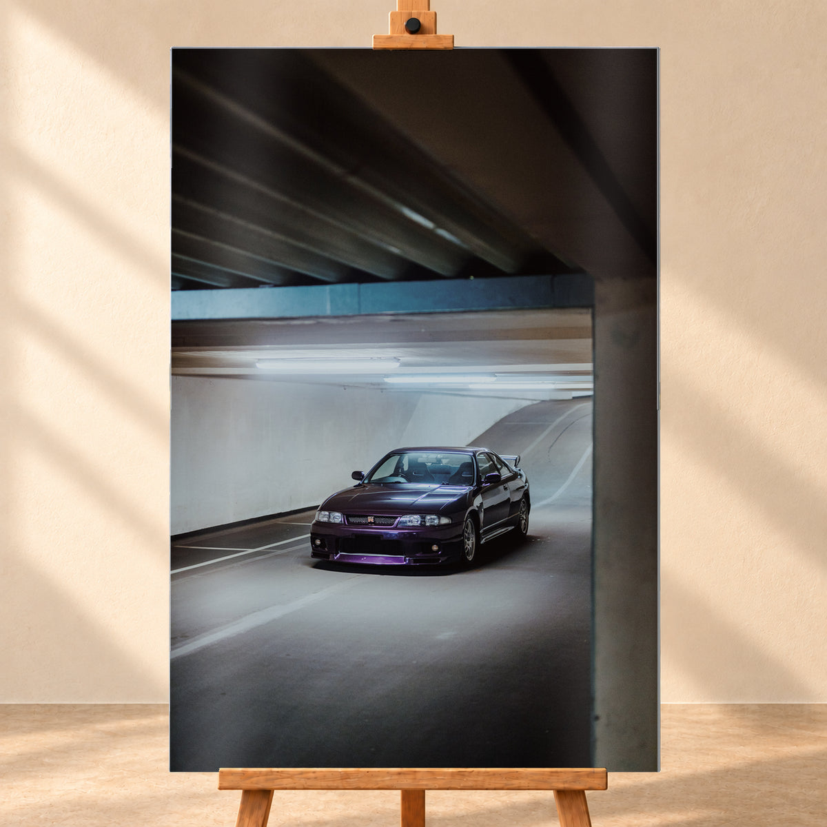 Dunkelvioletter Nissan Skyline in vorderer Dreiviertelansicht in einer Beton-Tiefgarage, beleuchtet von kühlen Deckenleuchten; Fahrbahnlinien und eine Rampe liegen im Hintergrund; Visualisierung als Alu gebürstet-Wandbild, frontal auf einer Holzstaffelei.