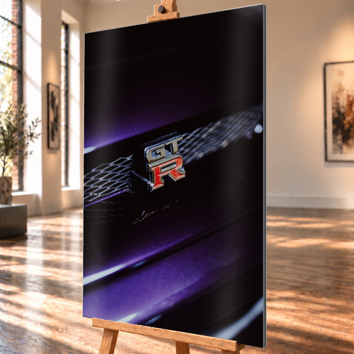 Nahaufnahme eines rot-silbernen GT-R-Emblems an einem dunklen Frontgrill, beleuchtet von violettem Licht und umgeben von tiefen Schatten; Visualisierung als Alu gebürstet-Wandbild, schräg von der Seite auf einer Holzstaffelei.