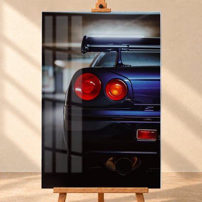 Hochformatige Nahaufnahme des Hecks eines dunkelblau-violetten Nissan Skyline V-Spec von 1999 in einem unscharfen, garagenartigen Innenraum; sichtbar sind zwei runde rote Rückleuchten, ein großer Heckflügel und ein rundes Auspuffendrohr am unteren Bildrand; Visualisierung als Acrylglas-Wandbild, frontal auf einer Holzstaffelei.