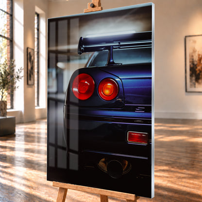 Hochformatige Nahaufnahme des Hecks eines dunkelblau-violetten Nissan Skyline V-Spec von 1999 in einem unscharfen, garagenartigen Innenraum; sichtbar sind zwei runde rote Rückleuchten, ein großer Heckflügel und ein rundes Auspuffendrohr am unteren Bildrand; Visualisierung als Acrylglas-Wandbild, schräg von der Seite auf einer Holzstaffelei.
