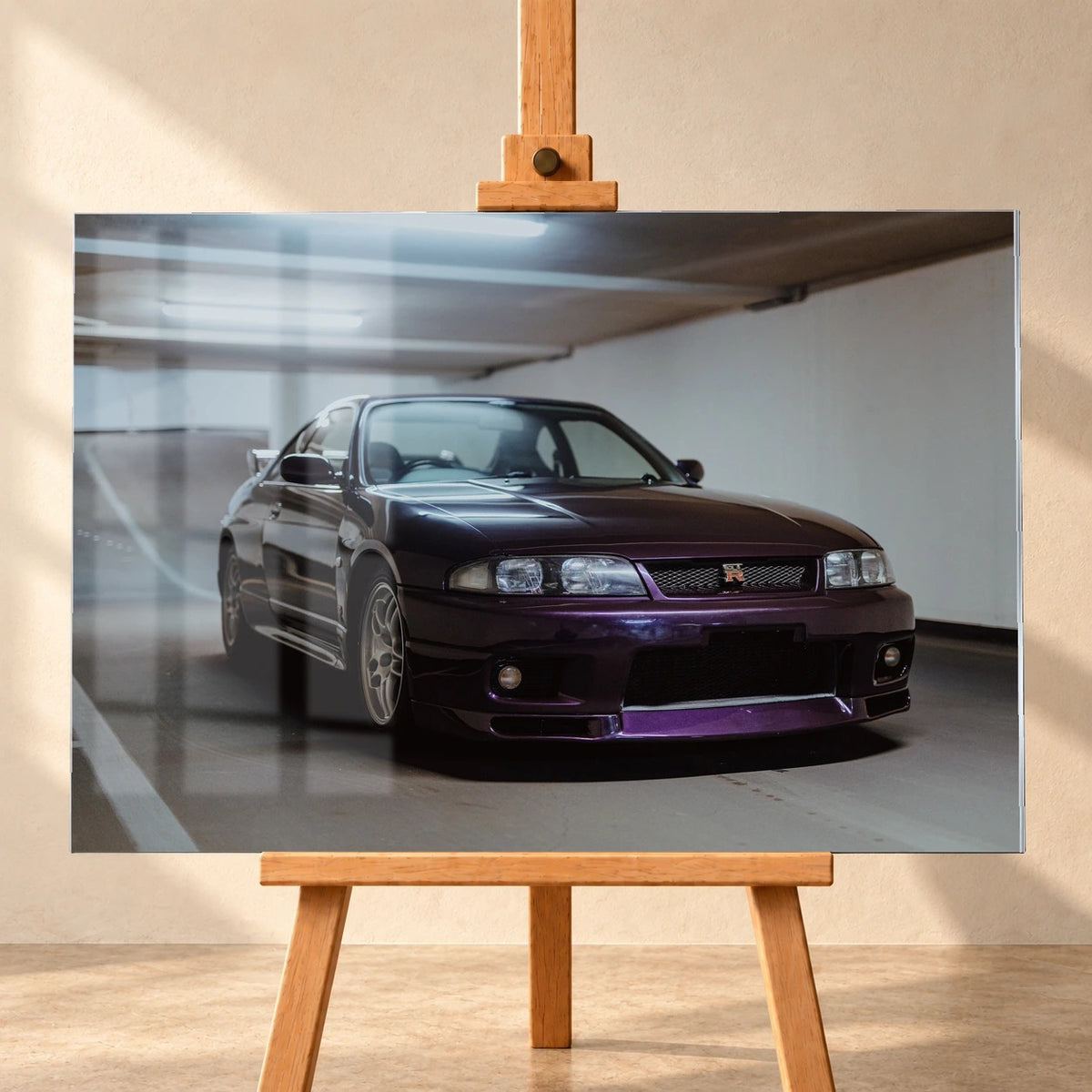 Der Nissan Skyline R33 steht tief in einer Dreiviertel-Frontansicht zwischen weißen Fahrbahnmarkierungen und kühlen Betonflächen. Motiv „Midnight Moment 2“ als Acrylglas-Wandbild, frontal auf einer Holzstaffelei.