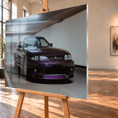 Der Nissan Skyline R33 steht tief in einer Dreiviertel-Frontansicht zwischen weißen Fahrbahnmarkierungen und kühlen Betonflächen. Motiv „Midnight Moment 2“ als Acrylglas-Wandbild, schräg von der Seite auf einer Holzstaffelei.
