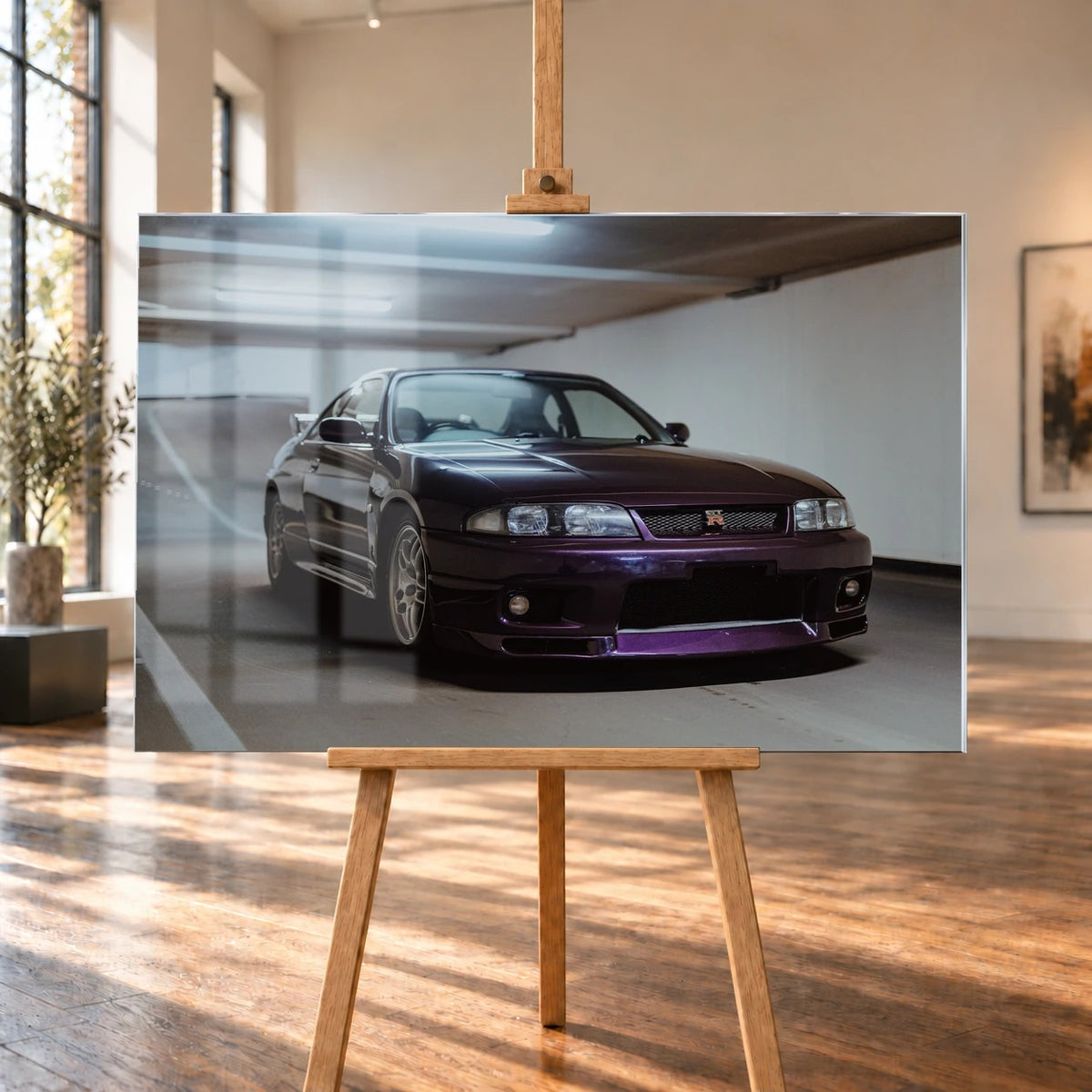 Der Nissan Skyline R33 steht tief in einer Dreiviertel-Frontansicht zwischen weißen Fahrbahnmarkierungen und kühlen Betonflächen. Motiv „Midnight Moment 2“ als Acrylglas-Wandbild, auf einer Holzstaffelei in einem hellen Galerieraum.