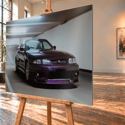 Der Nissan Skyline R33 steht tief in einer Dreiviertel-Frontansicht zwischen weißen Fahrbahnmarkierungen und kühlen Betonflächen. Motiv „Midnight Moment 2“ als Alu gebürstet-Wandbild, schräg von der Seite auf einer Holzstaffelei.