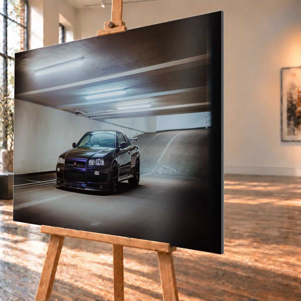 Der Nissan Skyline R34 nähert sich optisch aus einer breiten, geschwungenen Parkhausspur; das violette Auto steht im Zentrum des Lichtkegels. Motiv „Midnight Focus 2“ als Alu gebürstet-Wandbild, schräg von der Seite auf einer Holzstaffelei.