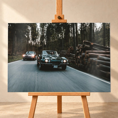 Eine grüne Corvette C2 und ein Porsche 911 S Softwindow fahren hintereinander durch einen Wald; Bewegungsunschärfe vermittelt Tempo. Motiv „Golden Light“ als Alu gebürstet-Wandbild, frontal auf einer Holzstaffelei.