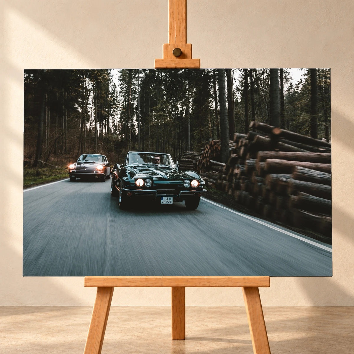 Eine grüne Corvette C2 und ein Porsche 911 S Softwindow fahren hintereinander durch einen Wald; Bewegungsunschärfe vermittelt Tempo. Motiv „Golden Light“ als Leinwand-Wandbild, frontal auf einer Holzstaffelei.