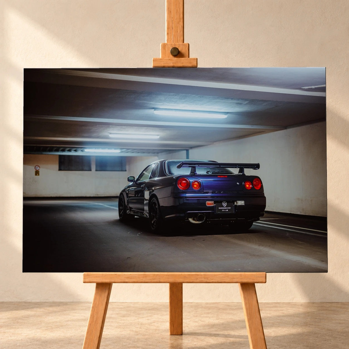 Der Nissan Skyline R34 steht schräg von hinten unter langen Deckenleuchten; Spoiler und rote Rundlichter führen die Perspektive. Motiv „Skyline Presence 2“ als Leinwand-Wandbild, frontal auf einer Holzstaffelei.