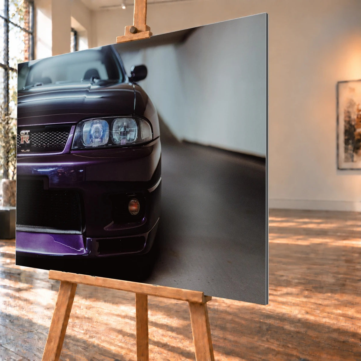 Die angeschnittene Front des Nissan Skyline R33 zeigt auf engem Raum Grill, Scheinwerfer und violetten Splitter als grafisches Detail. Motiv „Urban Horizon“ als Alu gebürstet-Wandbild, schräg von der Seite auf einer Holzstaffelei.