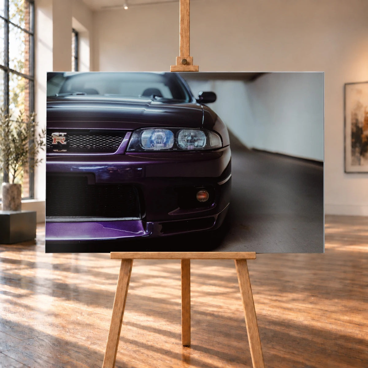Die angeschnittene Front des Nissan Skyline R33 zeigt auf engem Raum Grill, Scheinwerfer und violetten Splitter als grafisches Detail. Motiv „Urban Horizon“ als Alu gebürstet-Wandbild, auf einer Holzstaffelei in einem hellen Galerieraum.