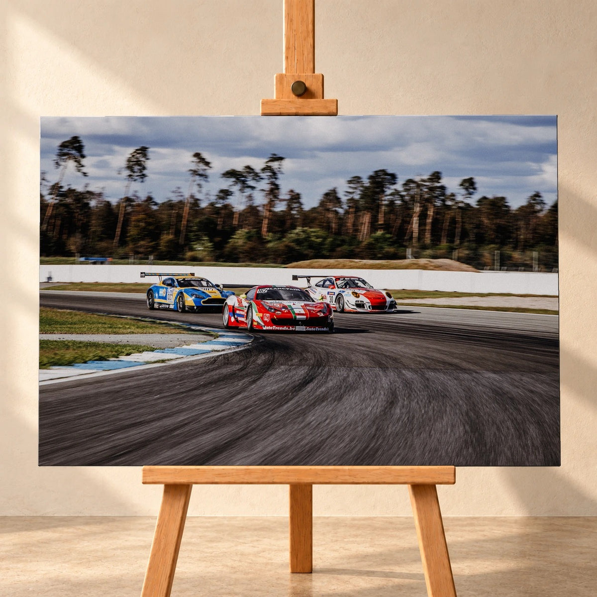 Aston Martin, Porsche und Ferrari GT3 fahren dicht gestaffelt durch eine Kurve; die Mehrwagen-Szene zeigt echtes Renngeschehen. Motiv „Racing Echo“ als Leinwand-Wandbild, frontal auf einer Holzstaffelei.
