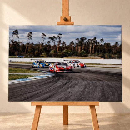 Aston Martin, Porsche und Ferrari GT3 fahren dicht gestaffelt durch eine Kurve; die Mehrwagen-Szene zeigt echtes Renngeschehen. Motiv „Racing Echo“ als Leinwand-Wandbild, frontal auf einer Holzstaffelei.