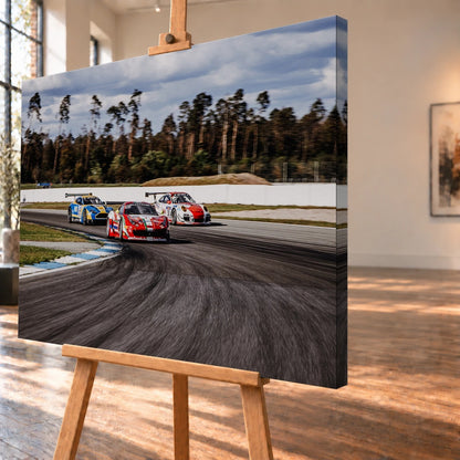 Aston Martin, Porsche und Ferrari GT3 fahren dicht gestaffelt durch eine Kurve; die Mehrwagen-Szene zeigt echtes Renngeschehen. Motiv „Racing Echo“ als Leinwand-Wandbild, schräg von der Seite auf einer Holzstaffelei.