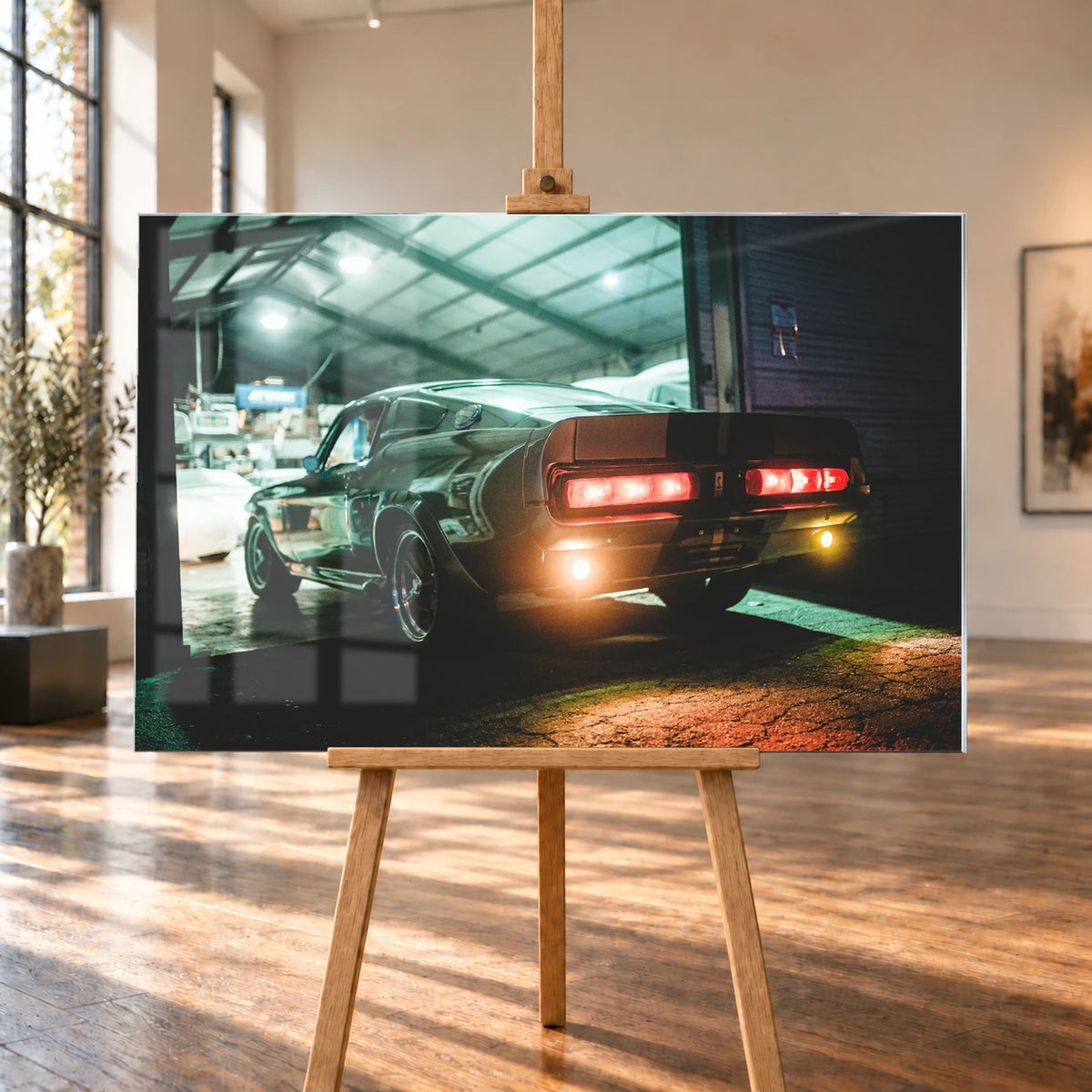 Eleanor steht von hinten in einer dunklen Werkhalle; rote Rücklichter und Spiegelungen auf nassem Boden erzeugen eine nächtliche Stimmung. Motiv „Cinematic Spirit“ als Acrylglas-Wandbild, auf einer Holzstaffelei in einem hellen Galerieraum.