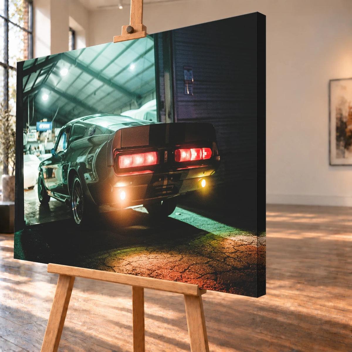 Eleanor steht von hinten in einer dunklen Werkhalle; rote Rücklichter und Spiegelungen auf nassem Boden erzeugen eine nächtliche Stimmung. Motiv „Cinematic Spirit“ als Leinwand-Wandbild, schräg von der Seite auf einer Holzstaffelei.