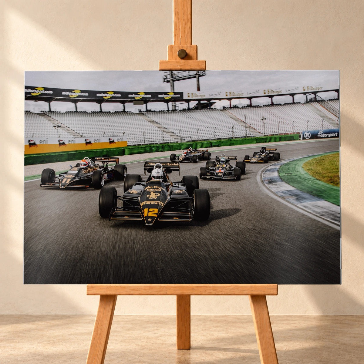 Fünf historische Lotus-Formelwagen fahren als Gruppe durch eine Rennstreckenkurve; schwarze Gold-Lackierungen und Startnummern sind deutlich erkennbar. Motiv „Trackside Story“ als Alu gebürstet-Wandbild, frontal auf einer Holzstaffelei.
