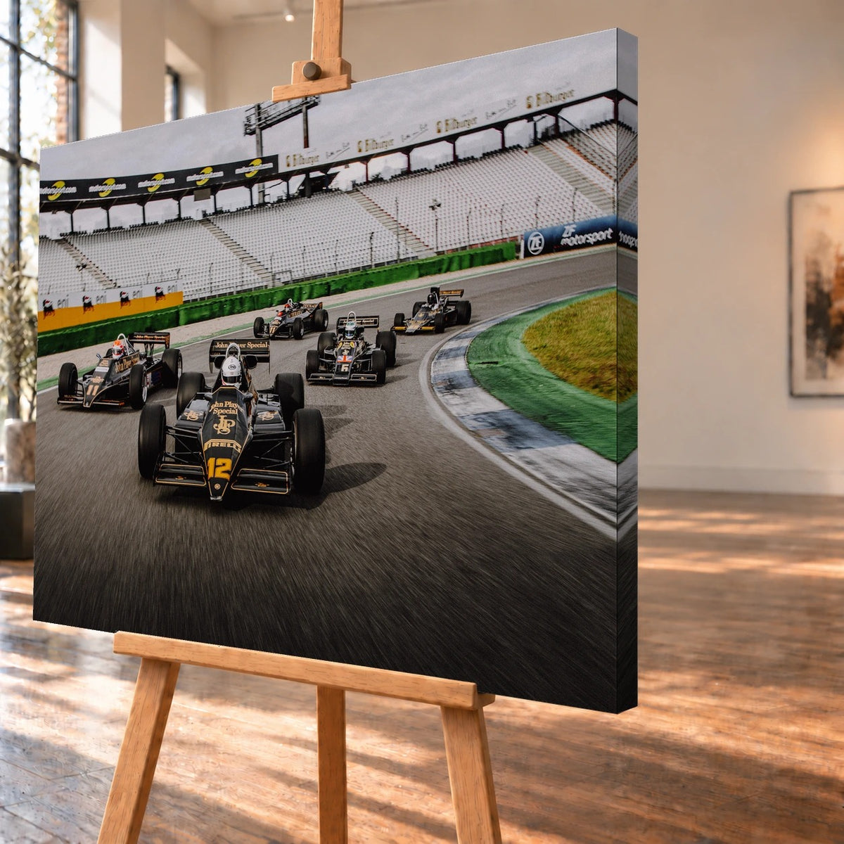 Fünf historische Lotus-Formelwagen fahren als Gruppe durch eine Rennstreckenkurve; schwarze Gold-Lackierungen und Startnummern sind deutlich erkennbar. Motiv „Trackside Story“ als Leinwand-Wandbild, schräg von der Seite auf einer Holzstaffelei.