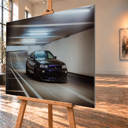 Der Nissan Skyline R34 steht tief und breit in der Kurve eines Parkhauses; Front, Seitenschweller und violette Akzente sind klar sichtbar. Motiv „Violet Story“ als Alu gebürstet-Wandbild, schräg von der Seite auf einer Holzstaffelei.