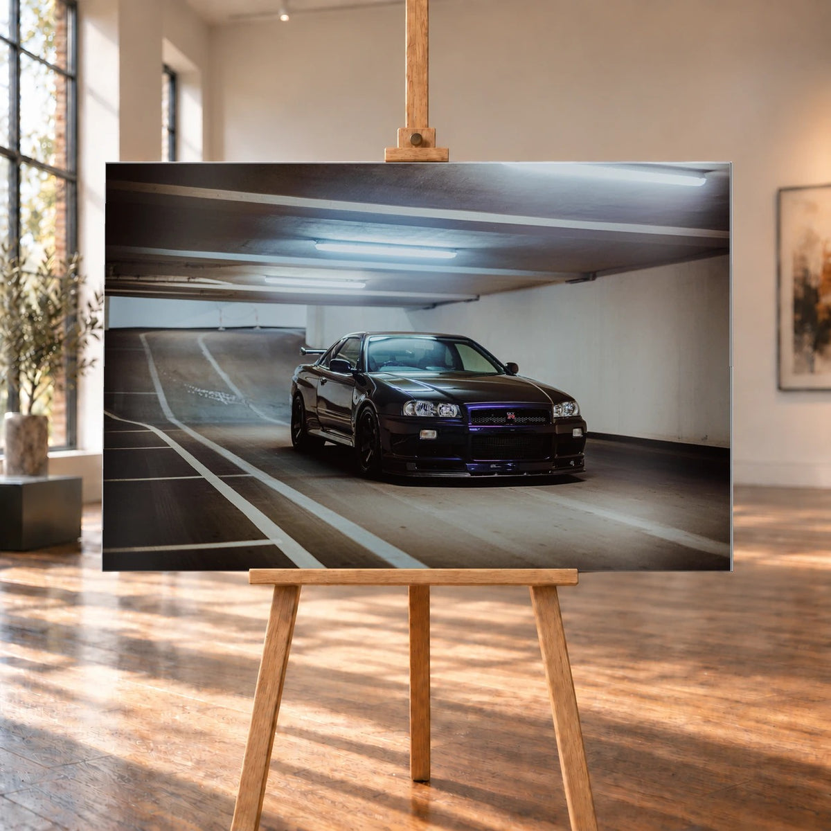 Der Nissan Skyline R34 steht tief und breit in der Kurve eines Parkhauses; Front, Seitenschweller und violette Akzente sind klar sichtbar. Motiv „Violet Story“ als Alu gebürstet-Wandbild, auf einer Holzstaffelei in einem hellen Galerieraum.