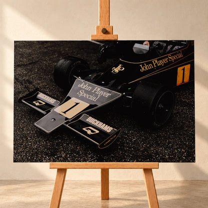Die Nahaufnahme zeigt die spitze Front des Lotus 76 mit goldener John-Player-Special-Lackierung und großer Startnummer 1. Motiv „Apex Story“ als Leinwand-Wandbild, frontal auf einer Holzstaffelei.